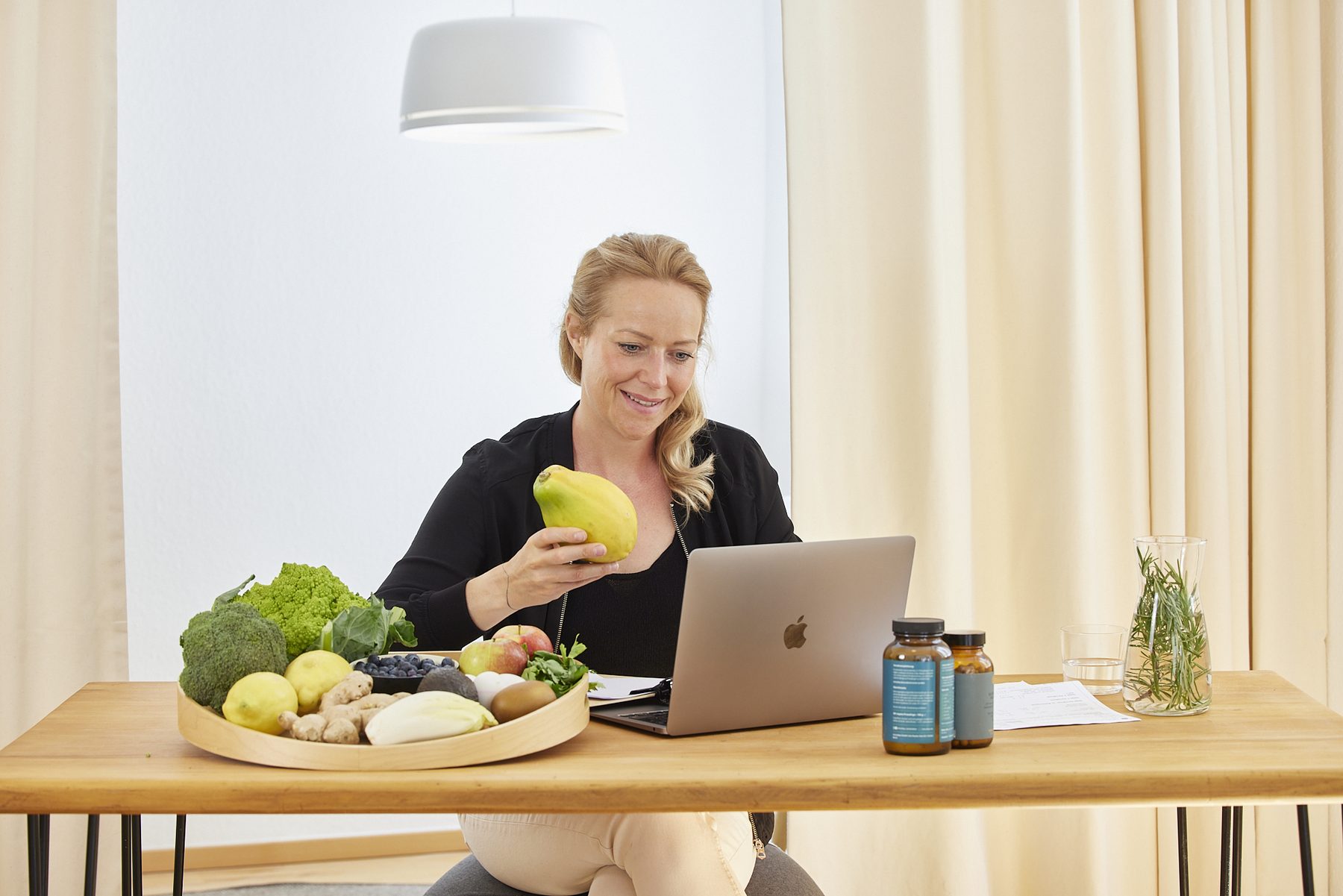 Sandra Maria Walz mit Lebensmitteln und Nährstoffen am Laptop